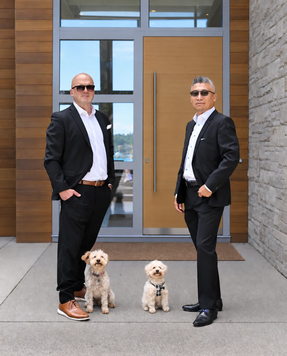 Daniel Ross and Daniel Low standing outside a home with their two dogs